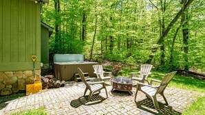 Un patio con una vasca idromassaggio, posti a sedere all'aperto e un muro in pietra.