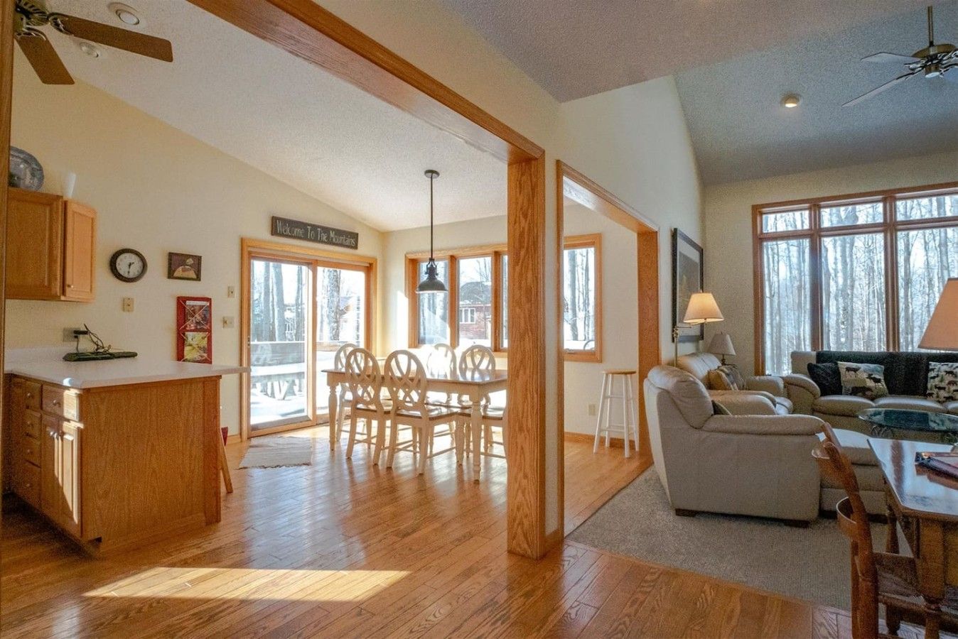A spacious living area with a dining table and chairs, a sofa, and a kitchen area with wooden cabinets and a countertop.