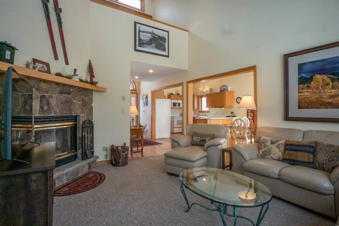 A cozy living room with a fireplace, a glass coffee table, and a sofa.