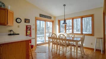 Une cuisine avec des meubles en bois, une table à manger avec des chaises, une horloge et une pancarte sur laquelle on peut lire : « Bienvenue à la montagne ».