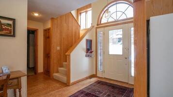 Un escalier en bois menant à un deuxième étage, une porte avec une pancarte indiquant «
Remontée mécanique
», et un tapis sur le sol.