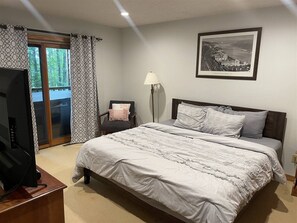 Una camera da letto con un letto, una sedia, un televisore e un quadro appeso al muro.