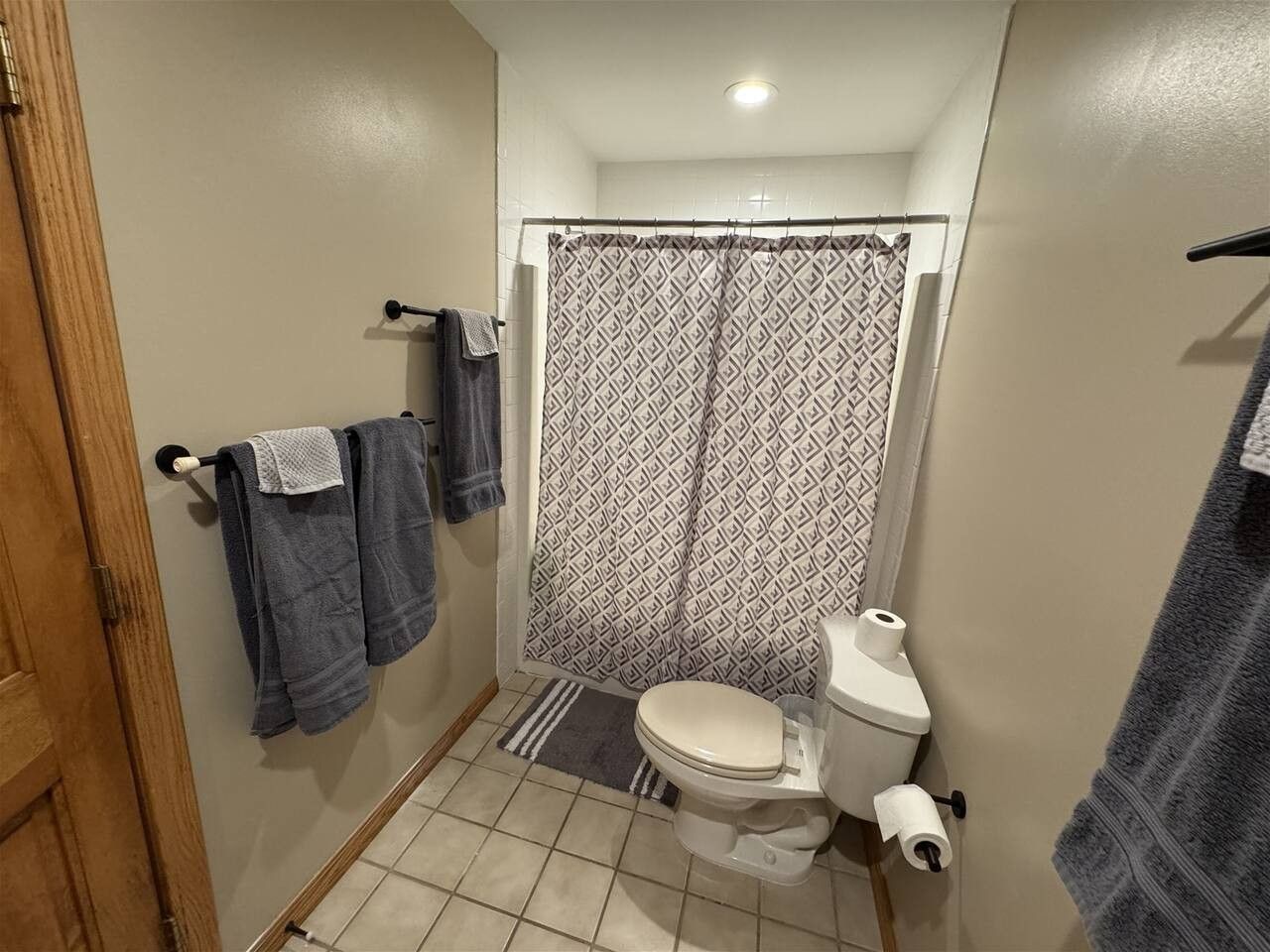 A bathroom with a toilet, a shower curtain, and towels hanging on a rack.