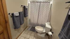 Ein Badezimmer mit Toilette, einer Duschvorhang und Handtüchern an einem Wäscheständer.