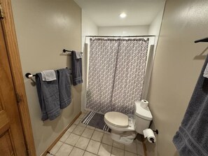 Un bagno con il water, una tenda per la doccia e asciugamani su un porta asciugamani.