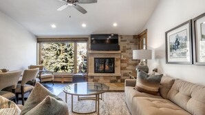 Una sala de estar moderna con chimenea, asientos cómodos y un amplio ventanal con vistas a un paisaje nevado.