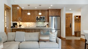 Una cocina moderna con armarios de madera, electrodomésticos de acero inoxidable e iluminación colgante.