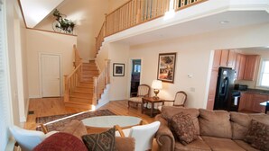 A spacious living room with a staircase, a dining area, and a kitchen.