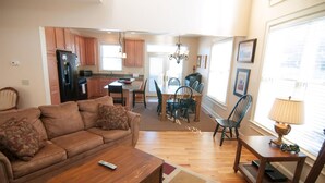 A living room with a brown sofa, a wooden coffee table, and a dining area with a table and chairs.