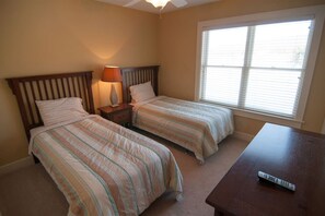 A bedroom with two beds, a nightstand with a lamp, a window with blinds, and a remote control on a table. - Aspen Village 34 - Air Conditioning, Hot Tub, Comm (Davis)