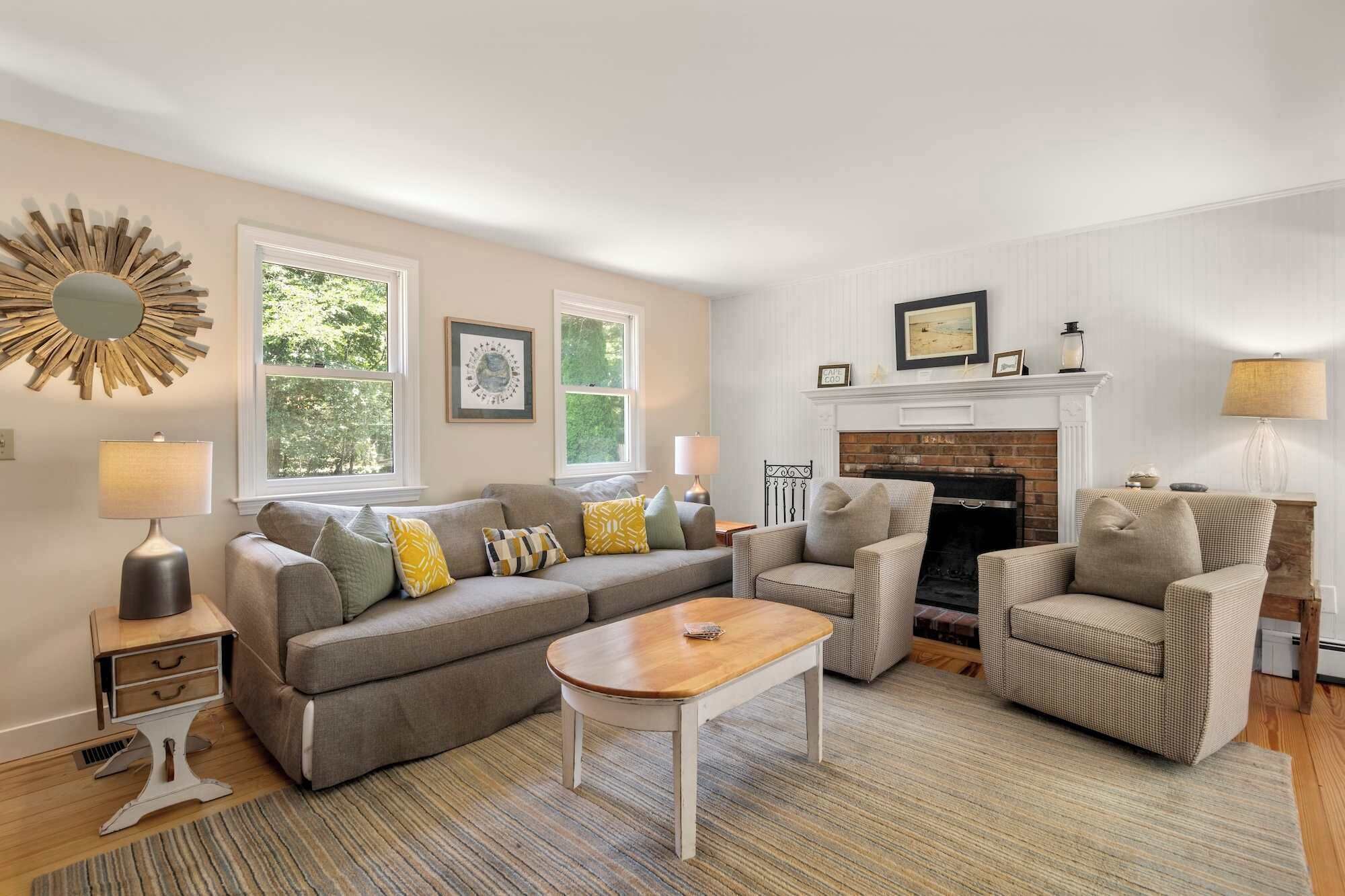 A living room with a fireplace, a sofa, a coffee table, and two armchairs.