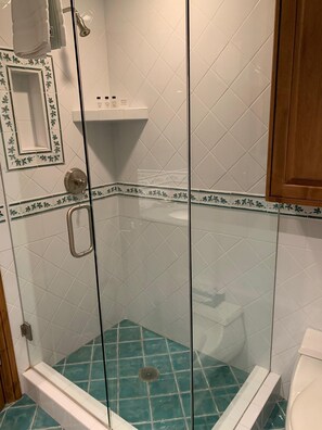 A glass-enclosed shower with a blue-tiled floor, a white sink, and a wooden cabinet. - Riva Ridge 720 | 2BR Vail Village (Vail)