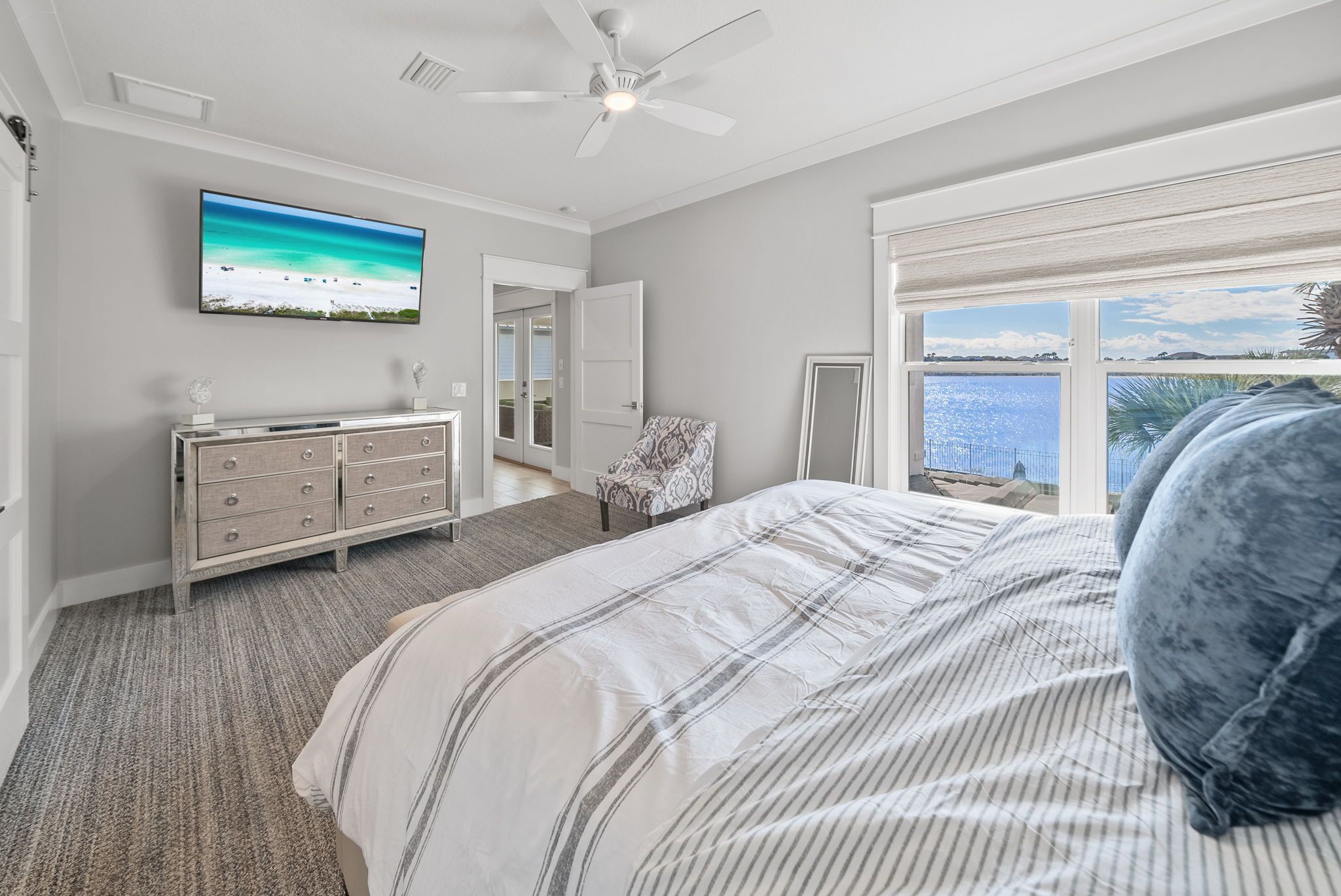 A bedroom with a bed, a dresser, a television, and a window with a view.