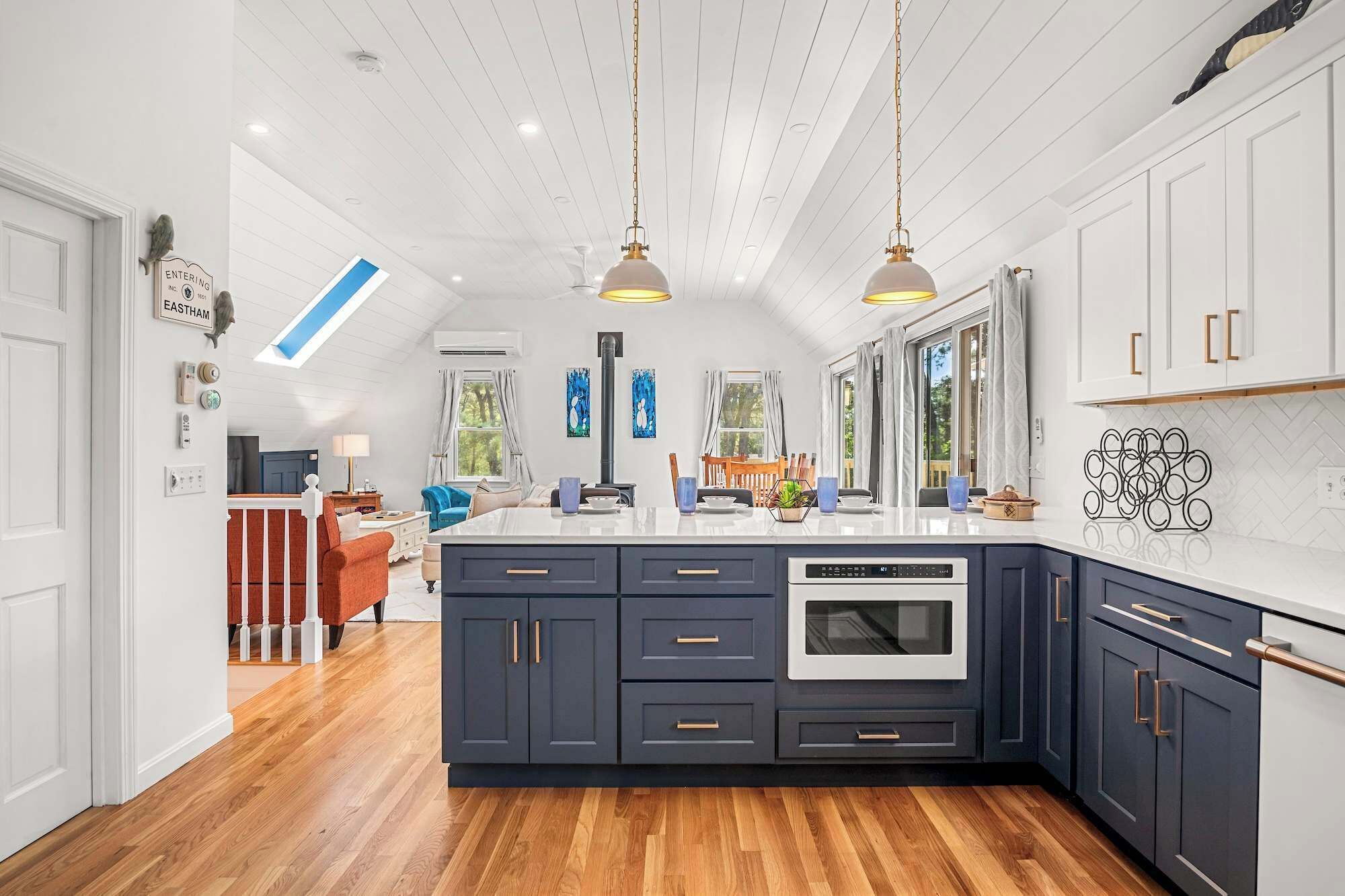 A modern kitchen with a large island, dark cabinetry, and pendant lighting.