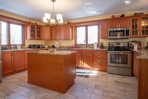 Una cocina con armarios de madera, una isla central, un microondas y un horno.