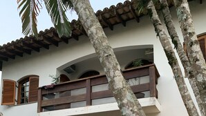 Un bâtiment à deux étages doté d’un balcon, de portes en arc de cercle et de plantes en pot.