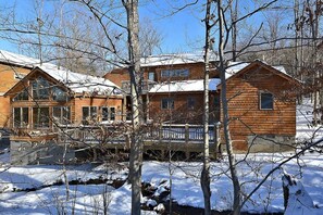 A wooden cabin with a balcony, surrounded by snow-covered trees.