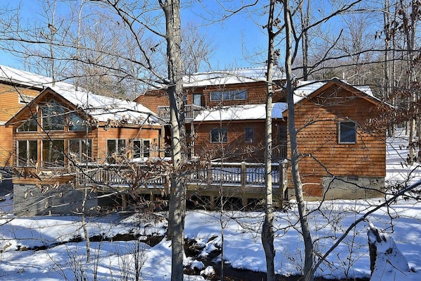 Una cabaña de madera con balcón, rodeada de árboles cubiertos de nieve.