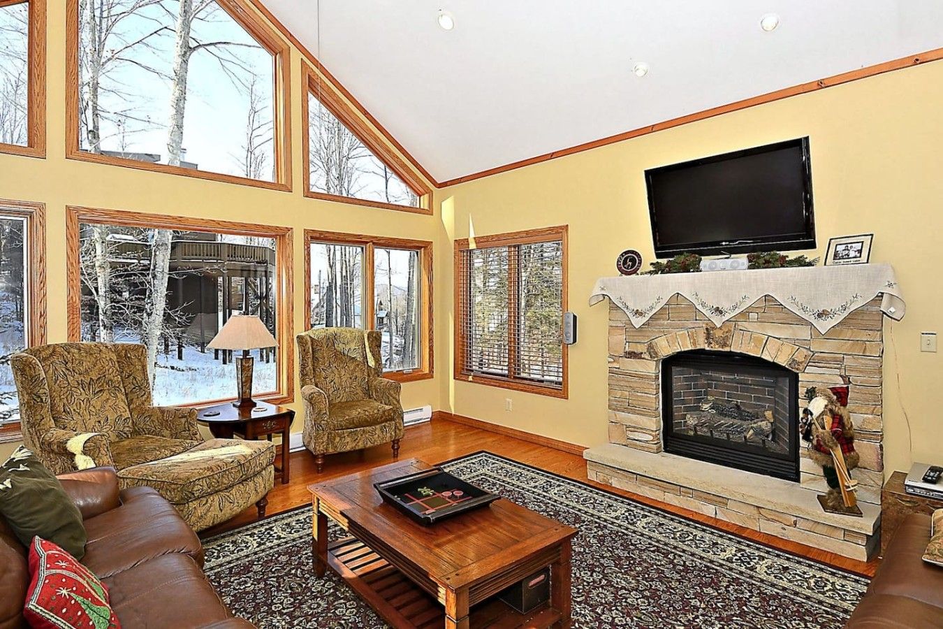 A spacious living room with a fireplace, large windows, and a television.