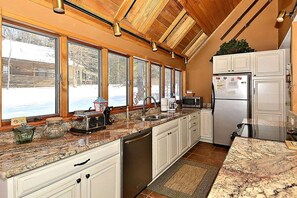 A kitchen with a large window, a sink, a microwave, and a refrigerator.