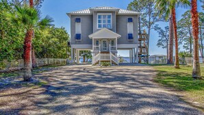 A two-story house with a covered porch, a wooden staircase, and a view of the water. - "Bayside Retreat" Panacea FL...Bay Front, Dock, 2 Large Porches, No Pets, Wifi (Panacea)