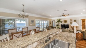 A spacious kitchen with granite countertops, a stainless steel sink, and a dining area with chairs and a table. - "Bayside Retreat" Panacea FL...Bay Front, Dock, 2 Large Porches, No Pets, Wifi (Panacea)