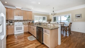A spacious kitchen with wooden cabinets, a granite countertop, stainless steel appliances, and a dining area with a large window. - "Bayside Retreat" Panacea FL...Bay Front, Dock, 2 Large Porches, No Pets, Wifi (Panacea)