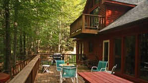 Una terraza de madera con mobiliario exterior y vistas a un bosque.