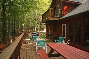 A wooden deck with outdoor seating and a view of a forest.