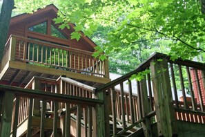 Een houten chalet met een balkon, omgeven door bomen.