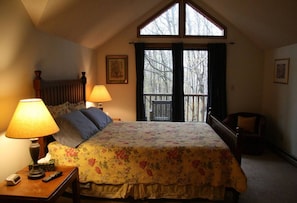 A bedroom with a bed, two bedside lamps, a window, and a chair.