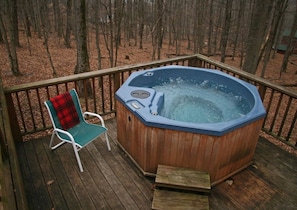 A wooden deck with a hot tub and a chair.