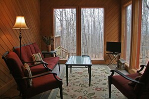 A cozy room with a sofa, armchairs, a table, and a TV.