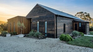 Una casa moderna de dos pisos con techo inclinado, ventanas grandes y entrada de grava.