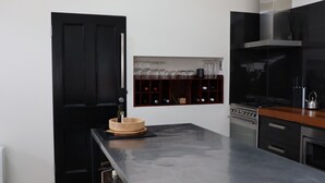 Una cocina moderna con armarios negros, una estantería empotrada para vinos y una estufa de acero inoxidable.