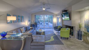 A modern living room with a glass coffee table, leather sofa, and a green armchair.