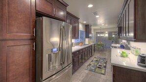 A modern kitchen with dark wooden cabinets, stainless steel appliances, and a breakfast bar.