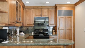 A kitchen with wooden cabinets, a stainless steel refrigerator, a stove, and a microwave. - Riva Ridge 715 | 2BR Vail Village (Vail)