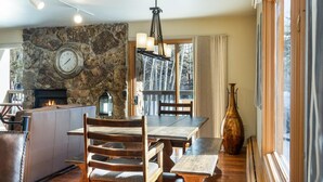 A cozy dining area with a stone wall, a fireplace, and a wooden table with chairs. - Riva Ridge 655 | 2BR Vail Village (Vail)