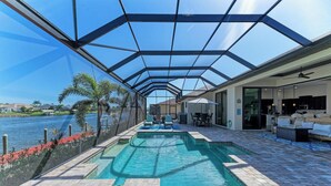 A swimming pool with a glass enclosure, outdoor seating, and a view of a body of water. - WATERFRONT LUXURY PRIVATE HEATED POOL&SPA/MIN TO BEACH/DOCK&LIFT/GULF ACCESS (Port Charlotte)
