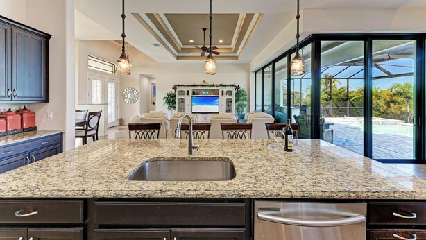 A kitchen with granite countertops, a stainless steel sink, dark cabinetry, and pendant lighting. - WATERFRONT LUXURY PRIVATE HEATED POOL&SPA/MIN TO BEACH/DOCK&LIFT/GULF ACCESS (Port Charlotte)