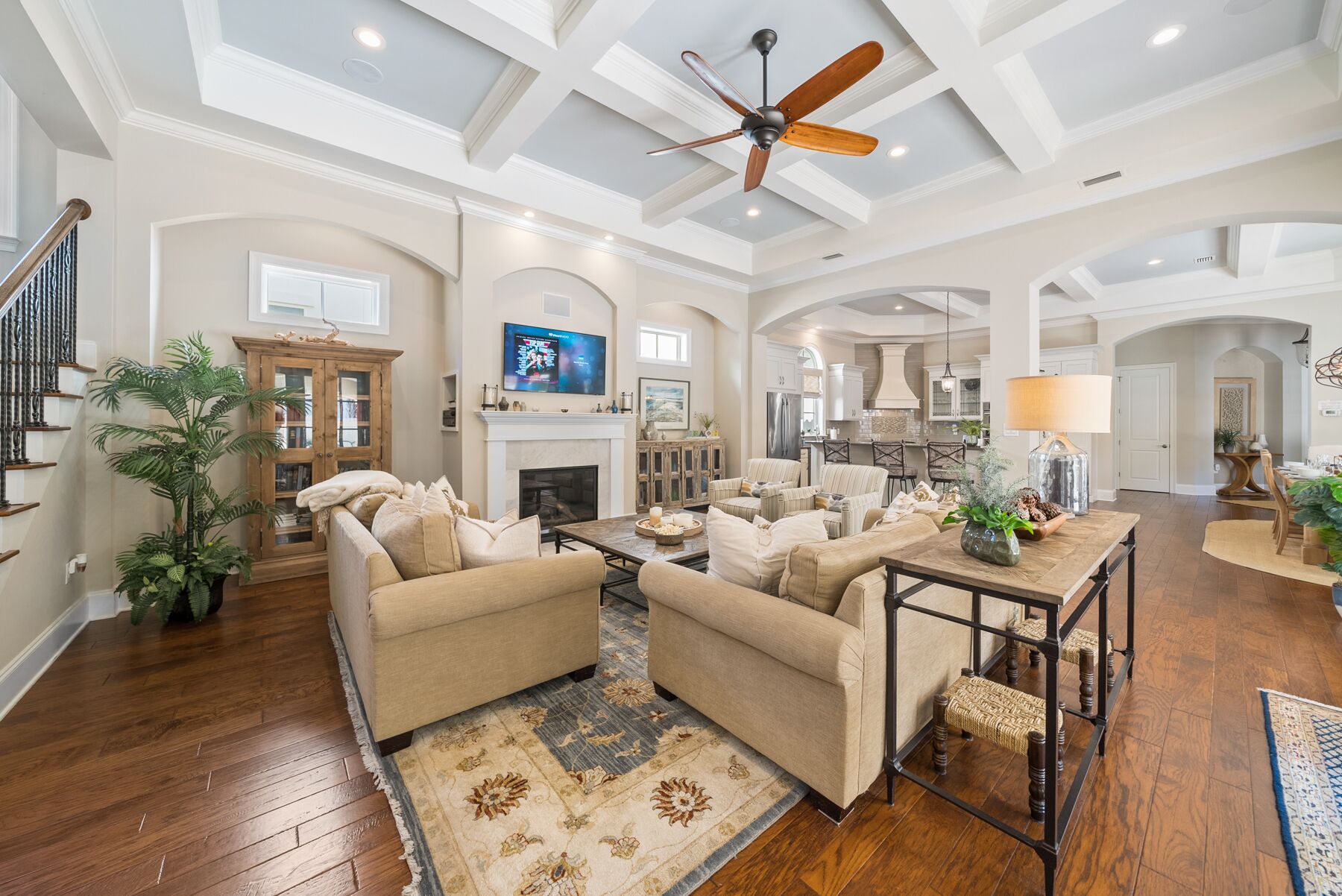 A spacious living room with a fireplace, comfortable seating, and a ceiling fan.