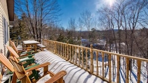 A wooden deck with outdoor seating, a railing, and a view of a snowy landscape. - Quiet, Peaceful Location, Walk to Everything, Hot Tub, Fireplace, Game Room (Lake Placid)