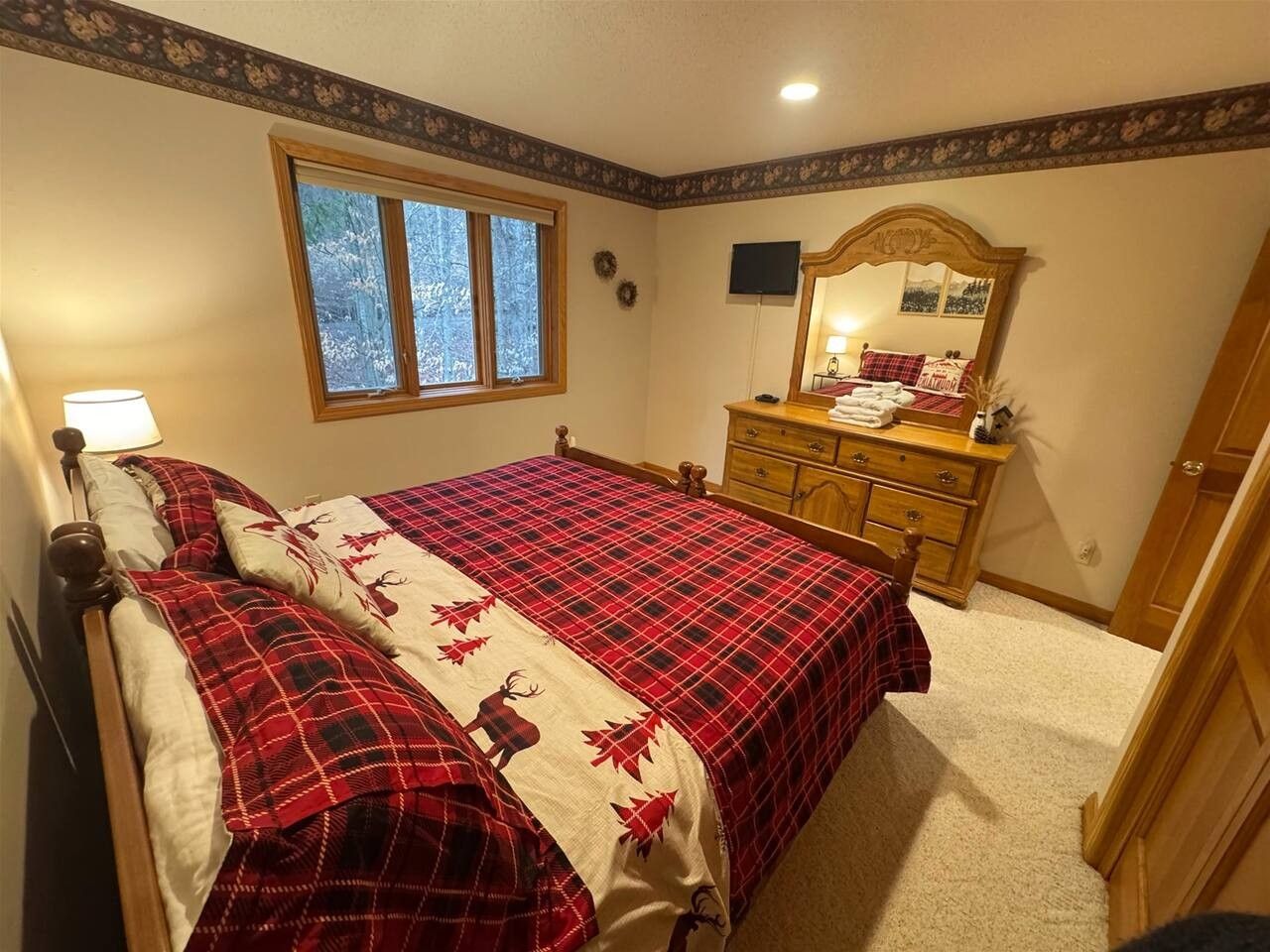Un dormitorio con cama, cómoda, espejo y ventana.