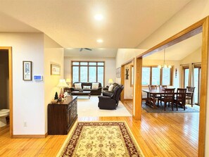 A spacious living room with a fireplace, a dining area with wooden furniture, and large windows providing natural light.