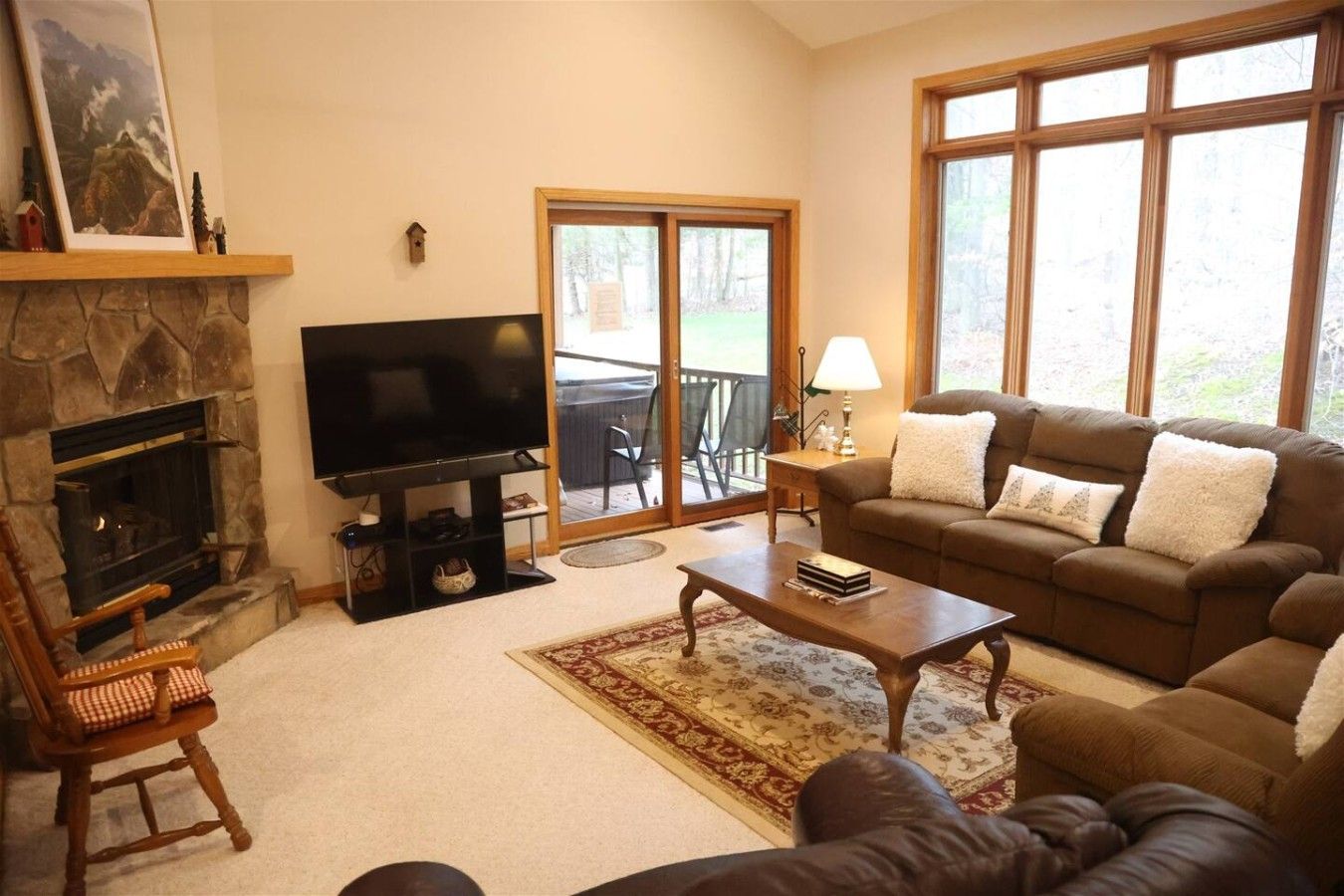 A living room with a fireplace, a television, a sofa, a coffee table, and a large window.