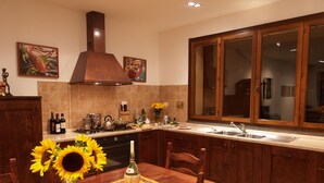 Une cuisine avec des meubles de rangement en bois, une cuisinière et un évier. Un vase rempli de tournesols est posé sur la table à manger.