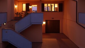 Un immeuble résidentiel à plusieurs étages, doté d’un escalier, de balcons et offrant une vue sur le ciel.