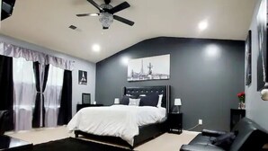 Ein modernes Schlafzimmer mit Bett, Schreibtisch, Stuhl, Deckenventilator und Nachttisch.