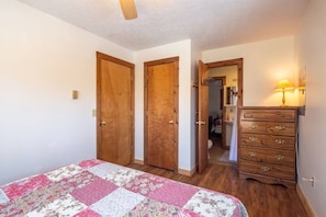 Ein Schlafzimmer mit einem Bett, einem Holzschrank und einer Tür zum Badezimmer.
